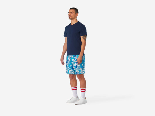 Full body side view of man wearing blue and white wave printed lounge shorts.