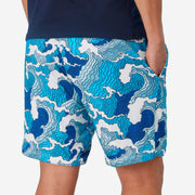 Close up back view of man wearing blue and white wave printed lounge shorts with hand in pocket.