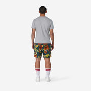 Fully body back view of man wearing green lounge shorts with tiger and snake print.