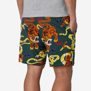 Back view of man wearing green lounge shorts with tiger and snake print with his hand in his pocket.